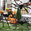 A large black spider decoration with long legs is displayed in front of a window decorated for Halloween.