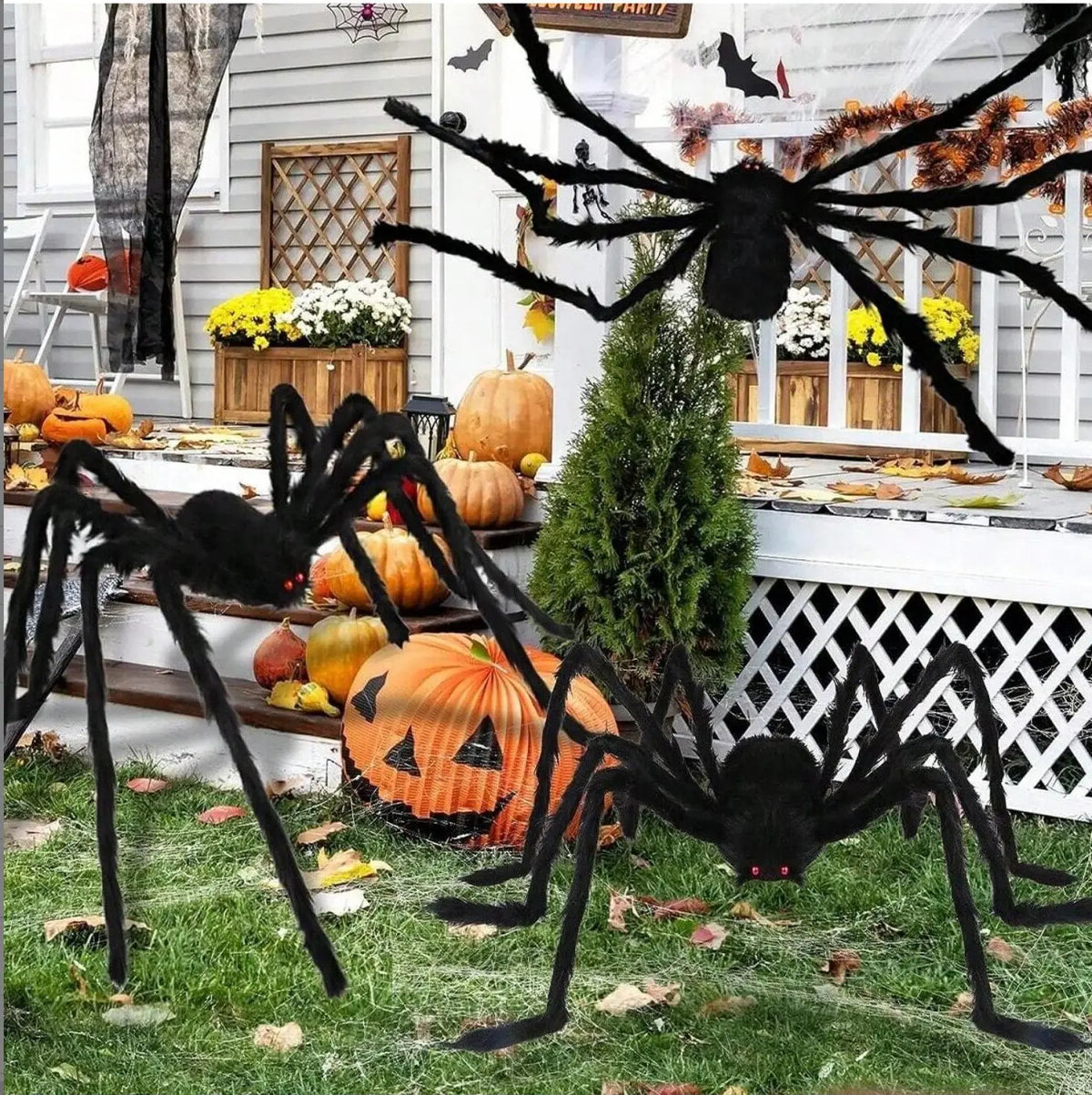 A large black spider decoration with long legs is displayed in front of a window decorated for Halloween.
