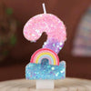 A sequined number candle shaped like a 9, featuring pink and purple glitter with a rainbow base.
