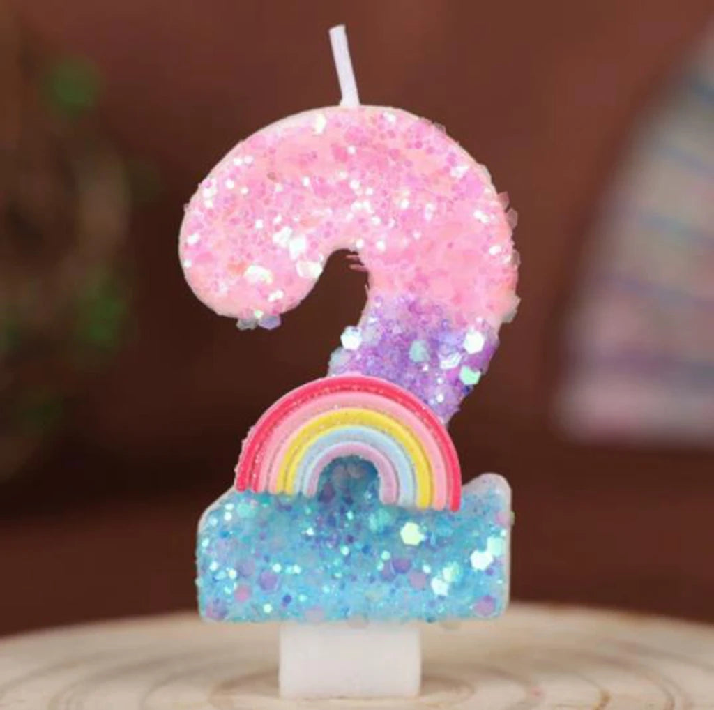 A sequined number candle shaped like a 9, featuring pink and purple glitter with a rainbow base.
