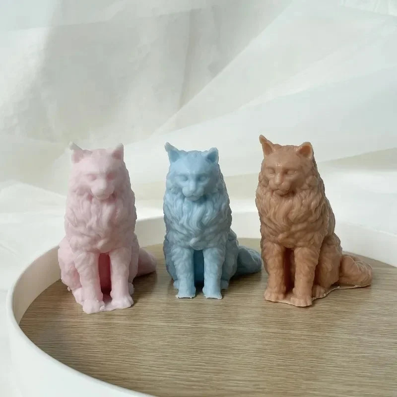 Three silicone cat molds in pink, blue, and brown sitting on a wooden surface.