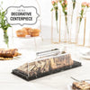 Clear acrylic cake stand with a lid displaying a rectangular marbleized dessert.