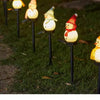 A row of solar powered outdoor Christmas snowman lights illuminating a grassy area.
