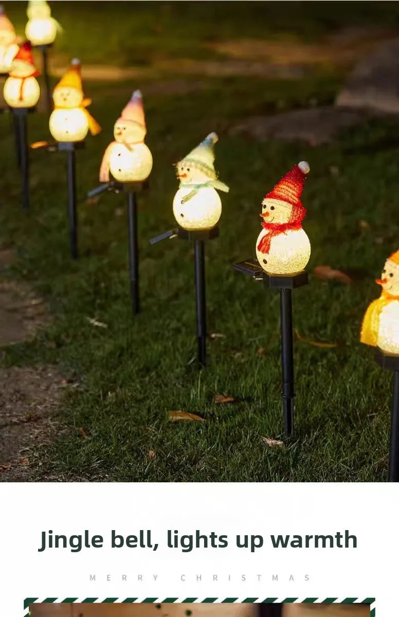 A row of solar powered outdoor Christmas snowman lights illuminating a grassy area.