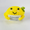 A yellow knitted plush doll resembling a lemon with a green top, featuring a smiling face and a tag that reads Positive Lemon
