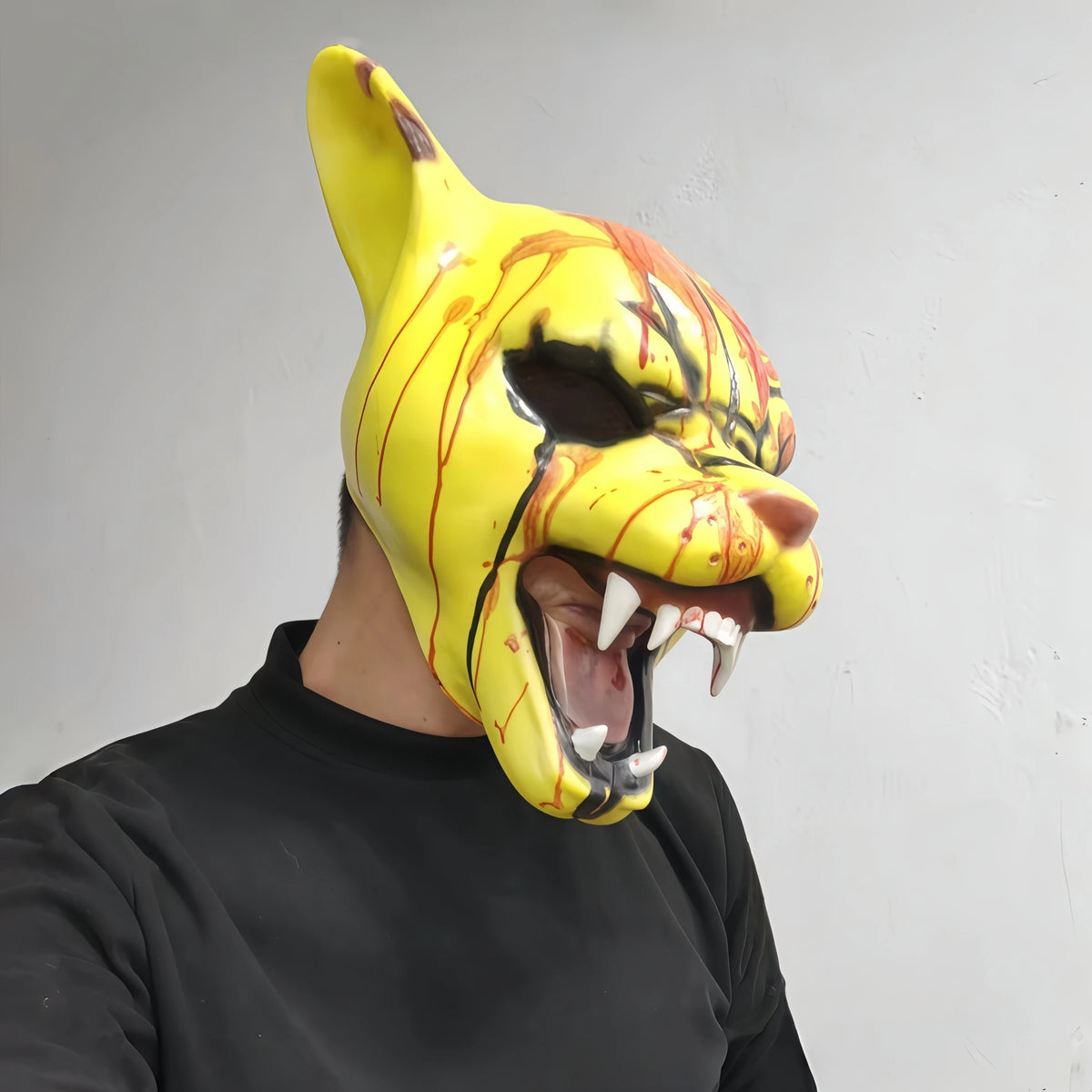A person is wearing a yellow and orange bloody tiger horror latex mask.