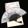 A vintage silk folding fan with delicate pink and white floral patterns is displayed against a light background.