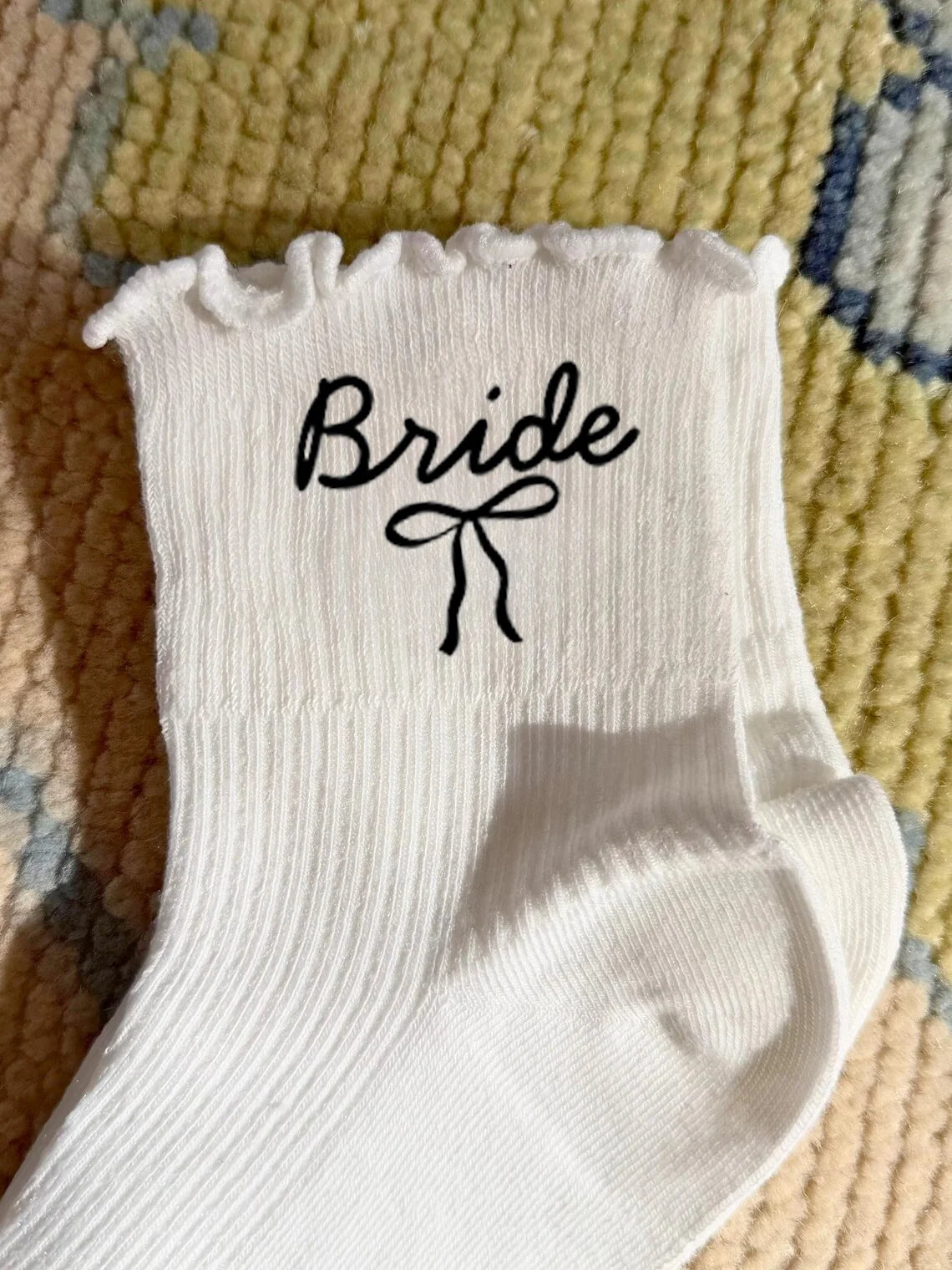 White knit socks with the word Bride embroidered on the foot section.