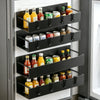 A black magnetic spice rack with multiple tiers holding various glass and plastic spice jars inside a refrigerator.