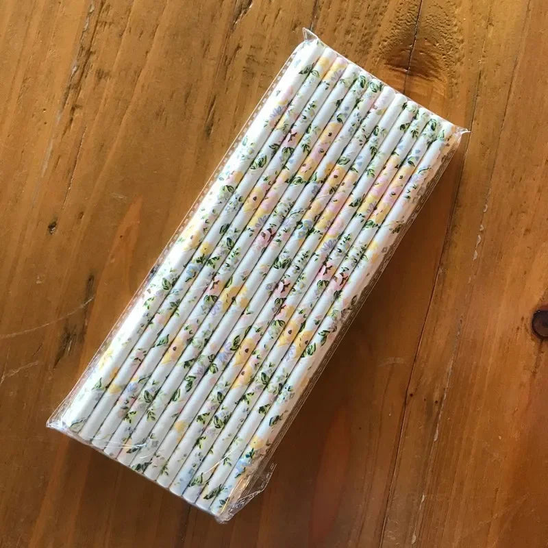A pack of 100 colorful striped and polka dot paper drinking straws lying on a wooden surface.