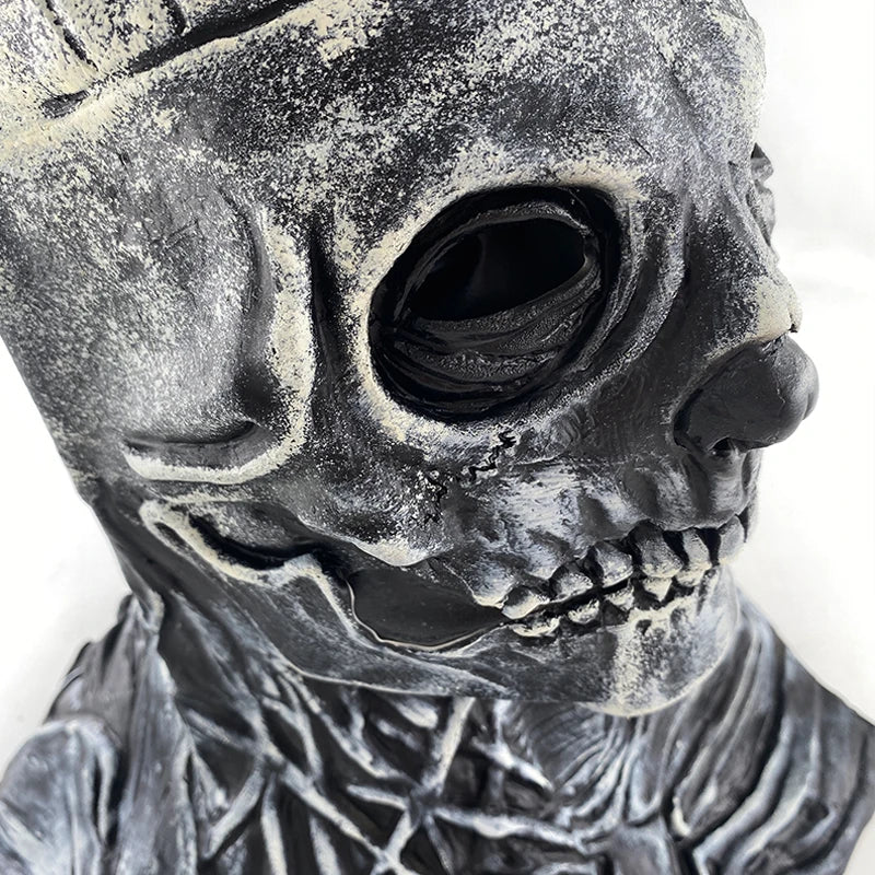 Gros plan d'un masque crâne en latex foncé et texturé avec des détails faciaux et osseux.