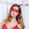 A woman wearing a red lace masquerade mask with long blonde hair against a white background.