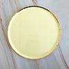 A round gold disposable party tableware set with plates resting on a marble surface.
