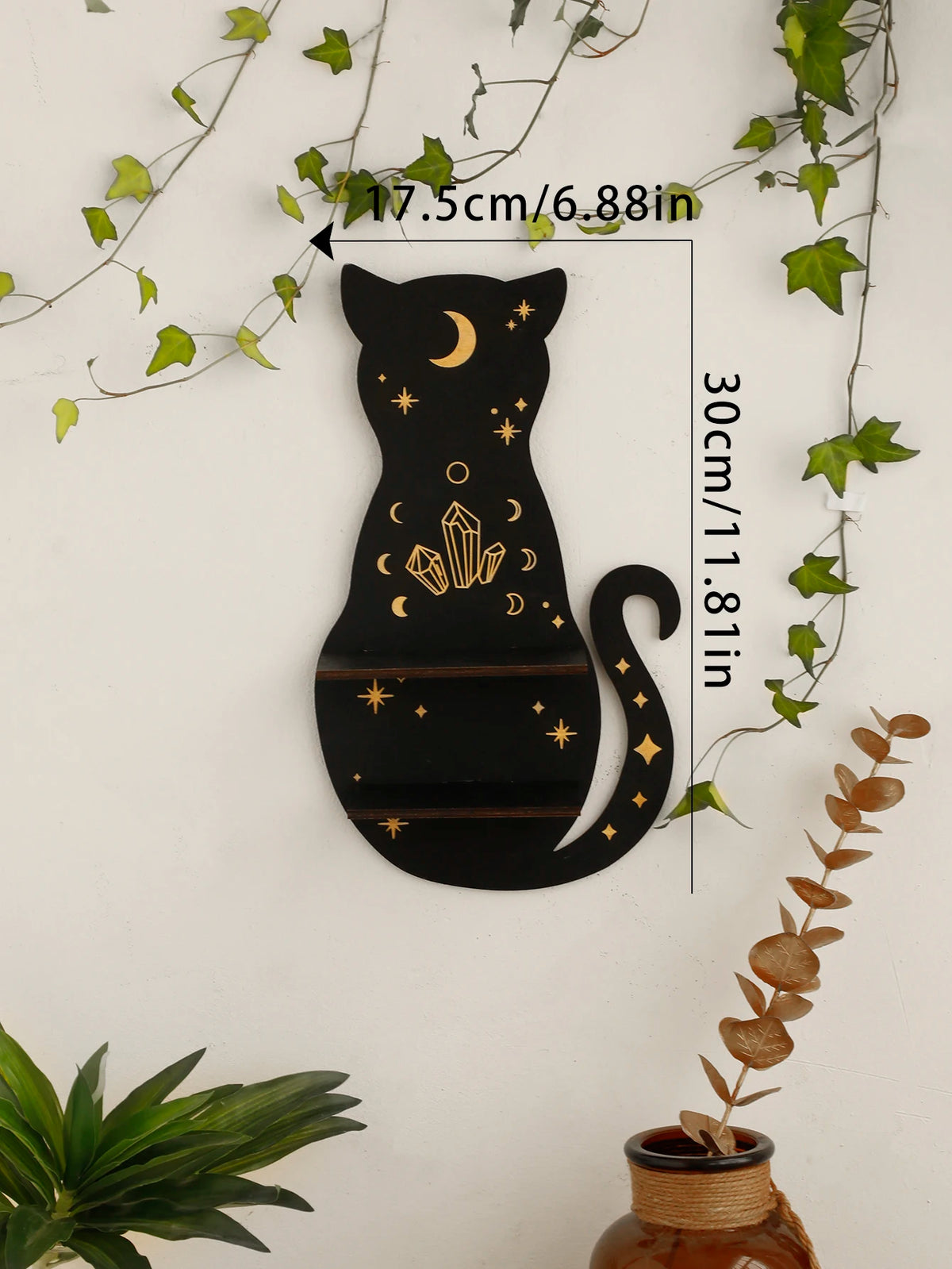 A black silhouette of a cat with a crescent moon and crystals on its body, displayed against a white wall.