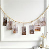 A white photo display garland featuring small framed photos hanging from a string against a white wall.