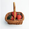 A woven rattan storage basket holding three fresh strawberries.