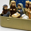 A pocket-sized nativity scene featuring figures of Mary Joseph and baby Jesus in a gold metal case.