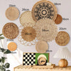 A collection of round boho straw wall hangings and woven tassels displayed on a wooden surface.