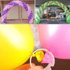 A hand holds a pink balloon arch connector ring with a small yellow bell.