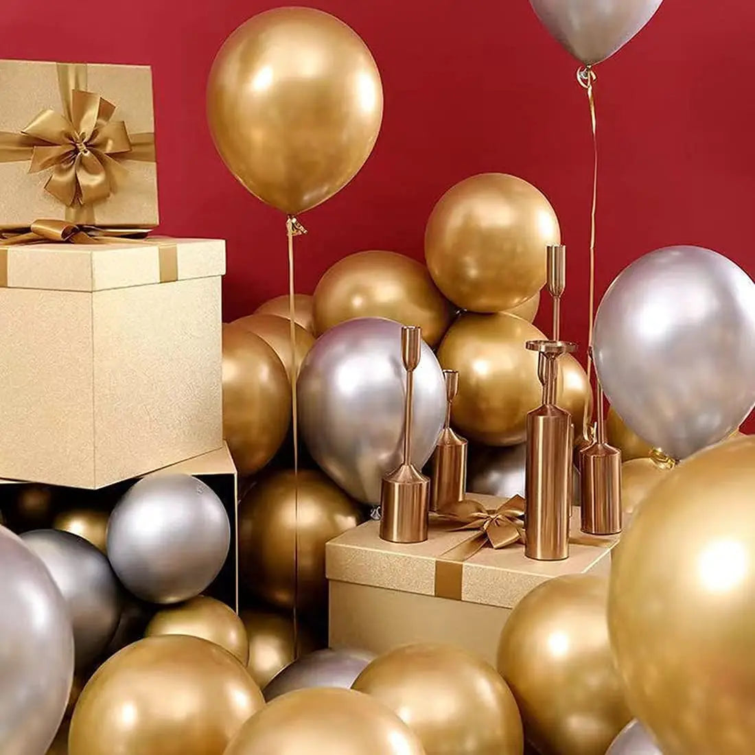 A display of chrome metallic gold and silver balloons on a red background.