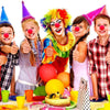 A colorful clown with bright hair and makeup is shown next to children, holding a red foam ball.