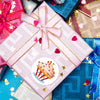 Pink gift box tied with a pink ribbon and gold accents, surrounded by other colorful wrapped presents.