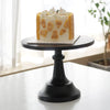 A layered white cake decorated with cream and orange accents displayed on a black metal cake stand.