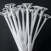 A close-up view of white balloon holder sticks arranged in a fan shape against a dark background.