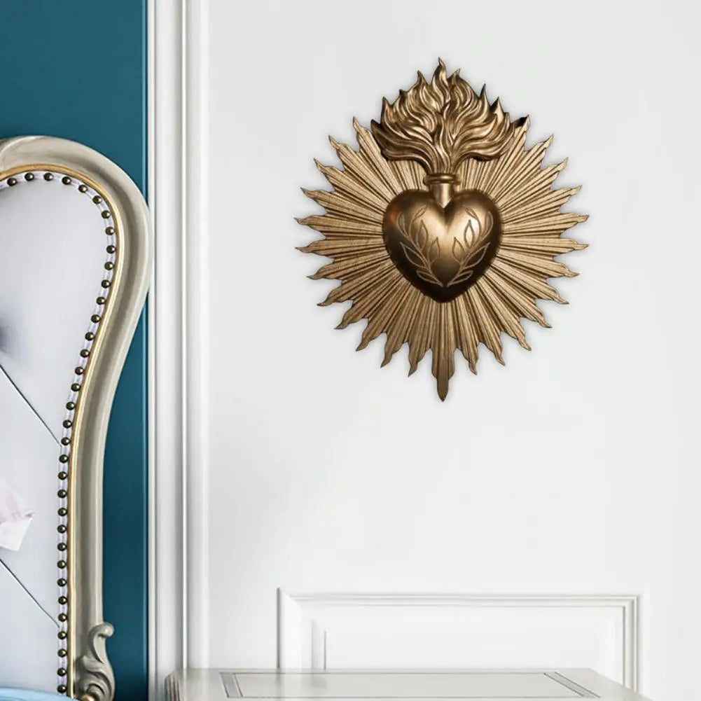 A gold-toned wall plaque featuring a sacred heart design with radiating rays.