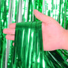 Une main tient un faisceau de rideaux à franges arc-en-ciel verts vifs.