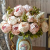 A bouquet of pink and cream peony artificial silk flowers arranged in a light blue vase.