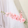 Un délicat jet de fleurs artificielles de delphinium roses arrangées sur un fond de tissu blanc transparent.