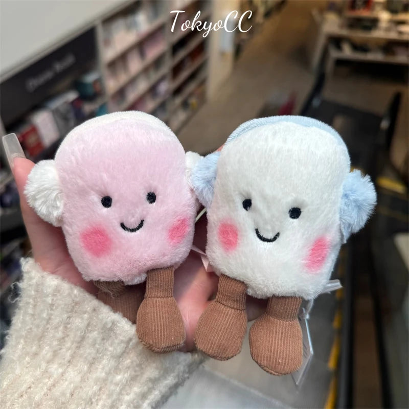 A pair of pink and light blue marshmallow plush toys held in a hand.