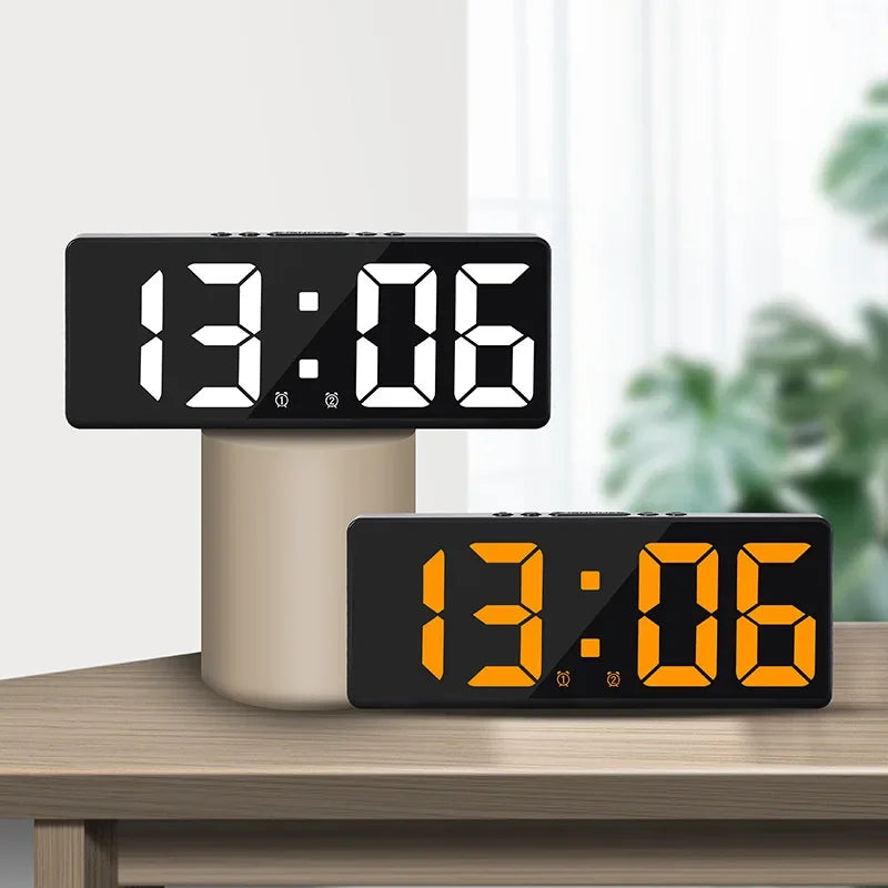 A black LED digital alarm clock displaying 13:06 on a wooden surface.