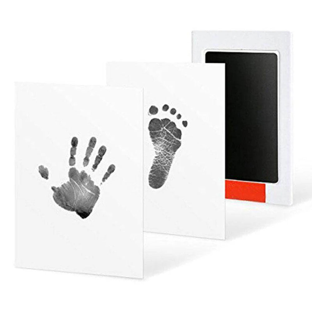 A white photo frame displaying a black handprint and footprint impression on the card.
