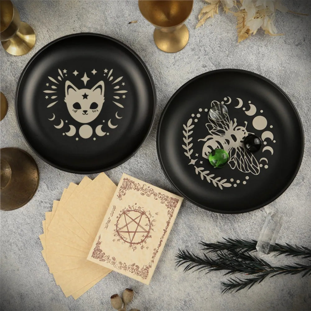 Assiette décorative noire avec silhouette de chat blanc et lunes de croissant, sur surface grise avec accents dorés.