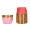 A stack of pink greaseproof cupcake liners with a gold rim and a pink paper cone top.