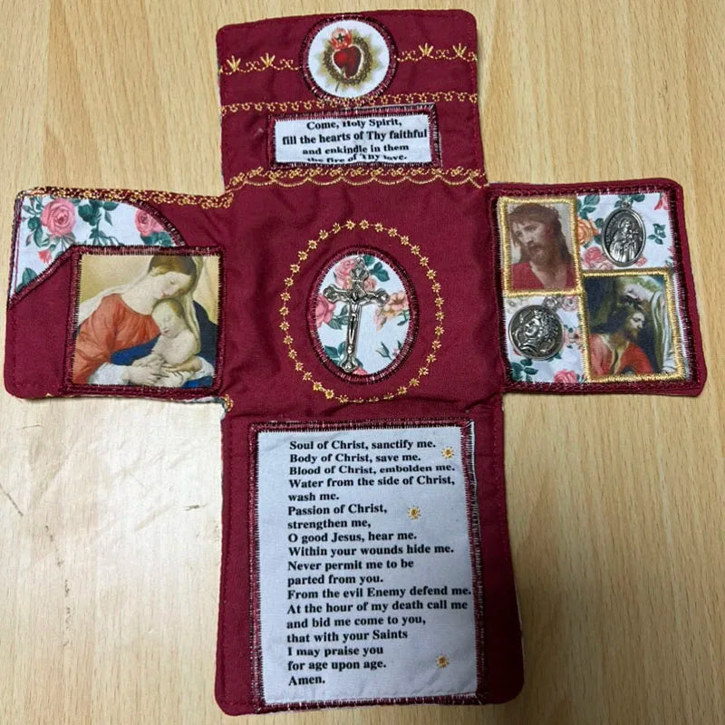 A handcrafted pocket shrine featuring a cross and various religious images on a dark red fabric background.