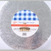 Round silver cake board with a blue checkered pattern and a wooden presentation stand.