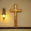 A wooden crucifix with a gold Jesus figure mounted on a light-colored wall.