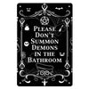 A black metal wall sign featuring a spooky design with text that reads Please Don't Summon Demons in the Bathroom