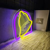 A glowing neon yellow bell-shaped sign is displayed on a white fluffy surface.