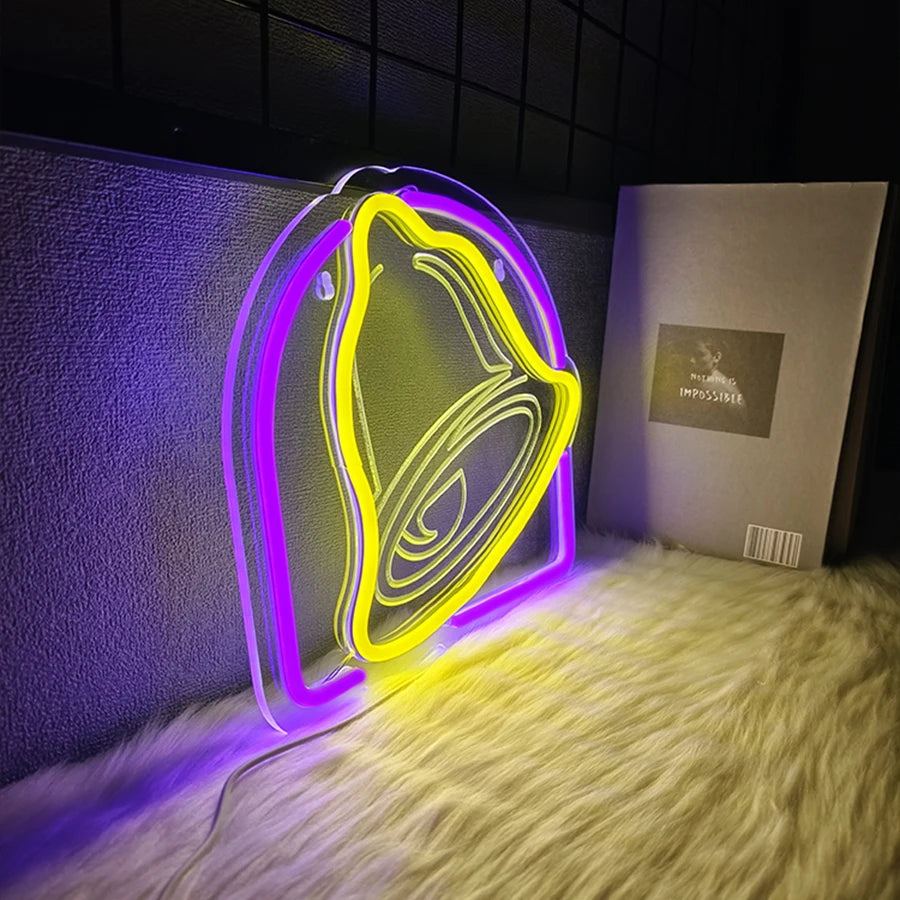 A glowing neon yellow bell-shaped sign is displayed on a white fluffy surface.