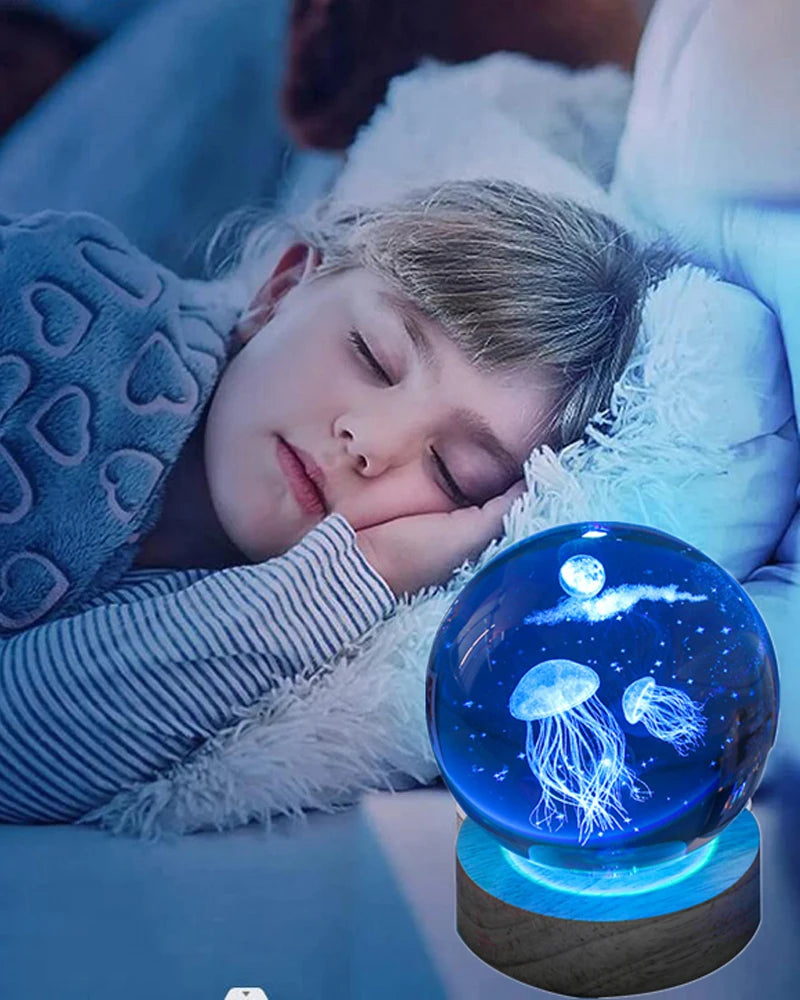 A young girl rests her head on a white fluffy blanket next to a blue crystal ball night light featuring glowing jellyfish.