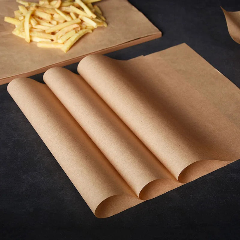 A stack of brown parchment paper rolls next to a pile of golden french fries on a dark surface.