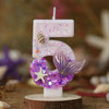 Pink birthday candle shaped like the number 5 decorated with glitter and purple mermaid tail accents