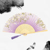 A vintage bamboo folding hand fan with purple accents and delicate floral patterns against a white background.
