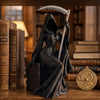 Dunkle Statue eines gotischen Erntemachers mit Sichel auf Holzoberfläche neben alten Büchern.