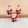 A set of festive Christmas resin decor featuring two Santa figures in red and white with beard and hat.