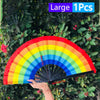 Large folding bamboo hand fan with a rainbow color gradient shown against green foliage.